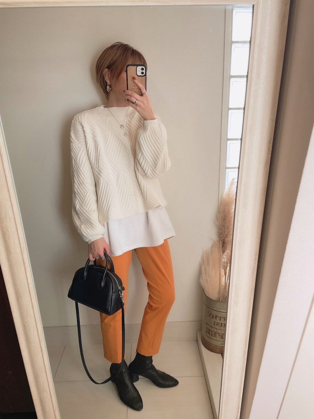 ホワイト系のニット/セーター、ブラック系のボストンバッグ、ブラック系のブーツを着用したレディースの冬コーディネートの2枚目の写真