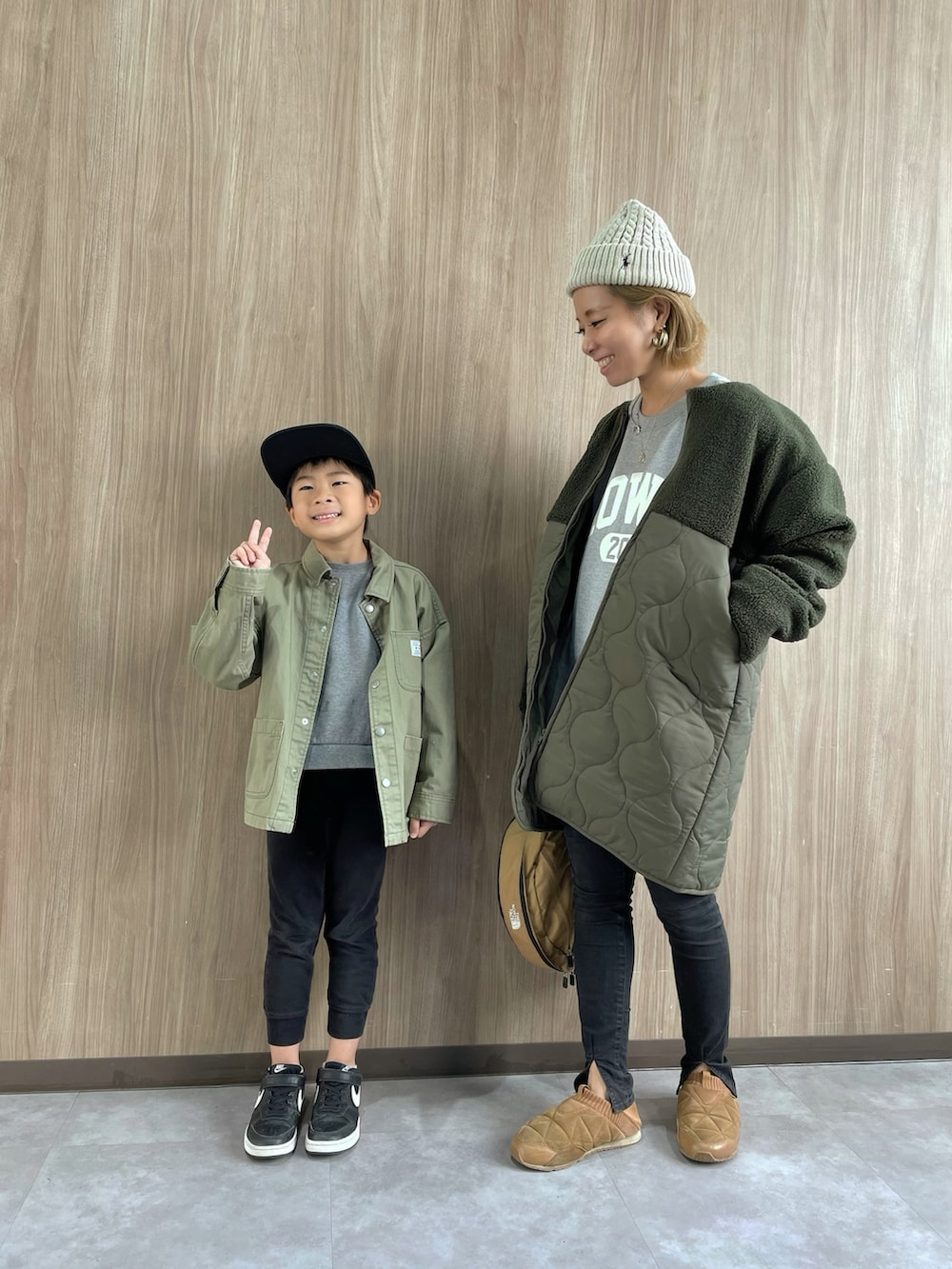 グリーン系のノーカラーコート、ブラウン系のボディバッグ/ウエストポーチ、ブラック系のデニムパンツを着用したレディースの秋コーディネートの3枚目の写真