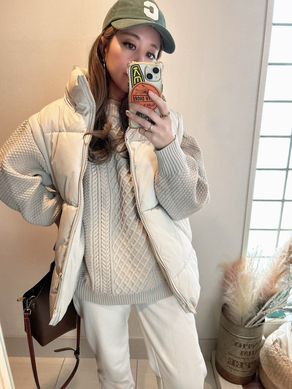 ベージュ系のニット/セーター、ベージュ系のダウンベスト、ブラウン系のブーツを着用したレディースの冬コーディネートの4枚目の写真