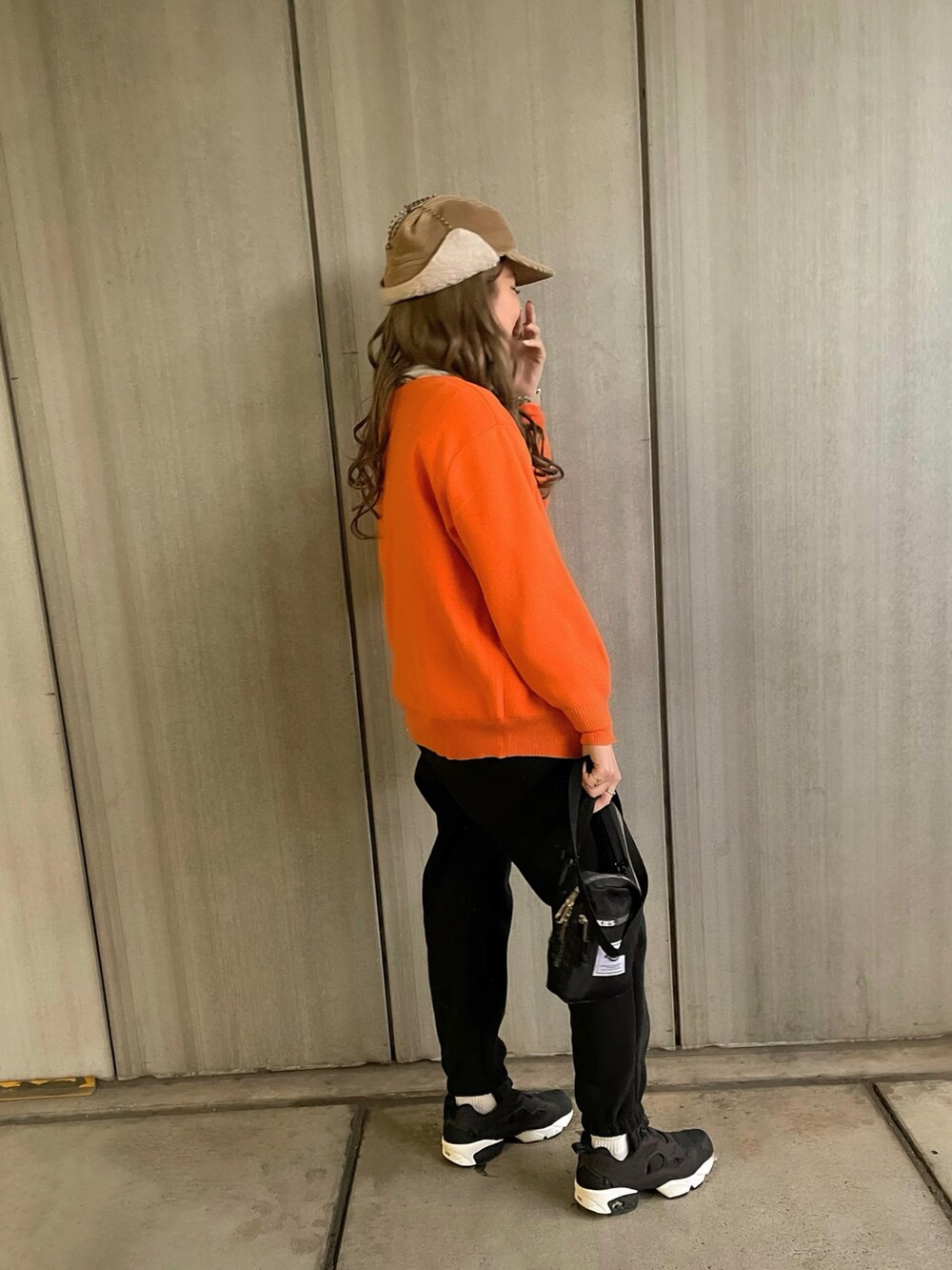 ブラック系のスニーカー、ブラック系のショルダーバッグ、ベージュ系のキャップを着用したレディースの冬コーディネートの2枚目の写真