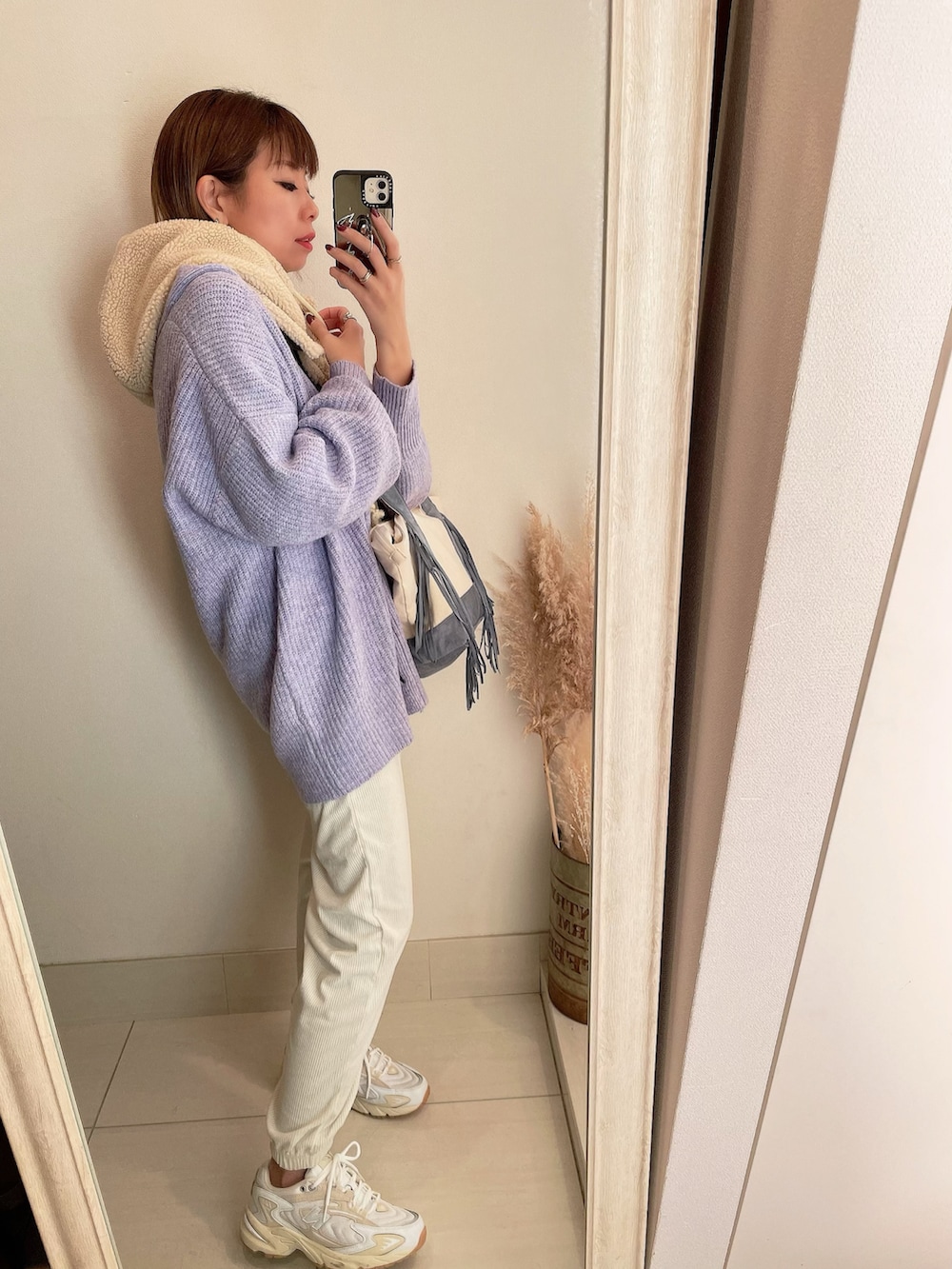 パープル系のカーディガン/ボレロ、ホワイト系のスニーカー、ベージュ系のマフラーを着用したレディースの冬コーディネートの2枚目の写真