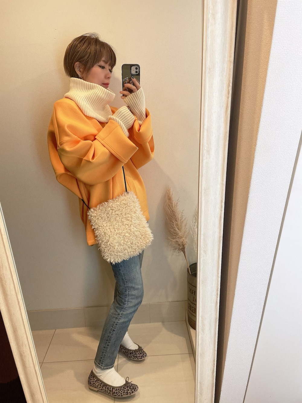 オレンジ系のスウェット、その他のバレエシューズ、ホワイト系のショルダーバッグを着用したレディースの冬コーディネートの2枚目の写真