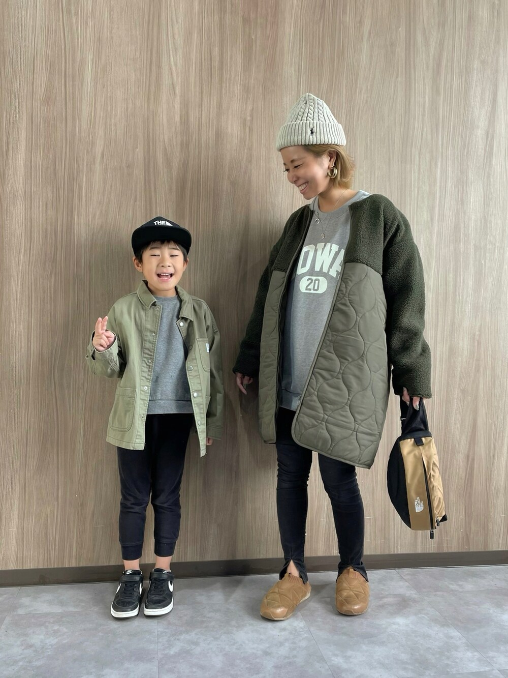 グリーン系のノーカラーコート、ブラウン系のボディバッグ/ウエストポーチ、ブラック系のデニムパンツを着用したレディースの秋コーディネートの2枚目の写真