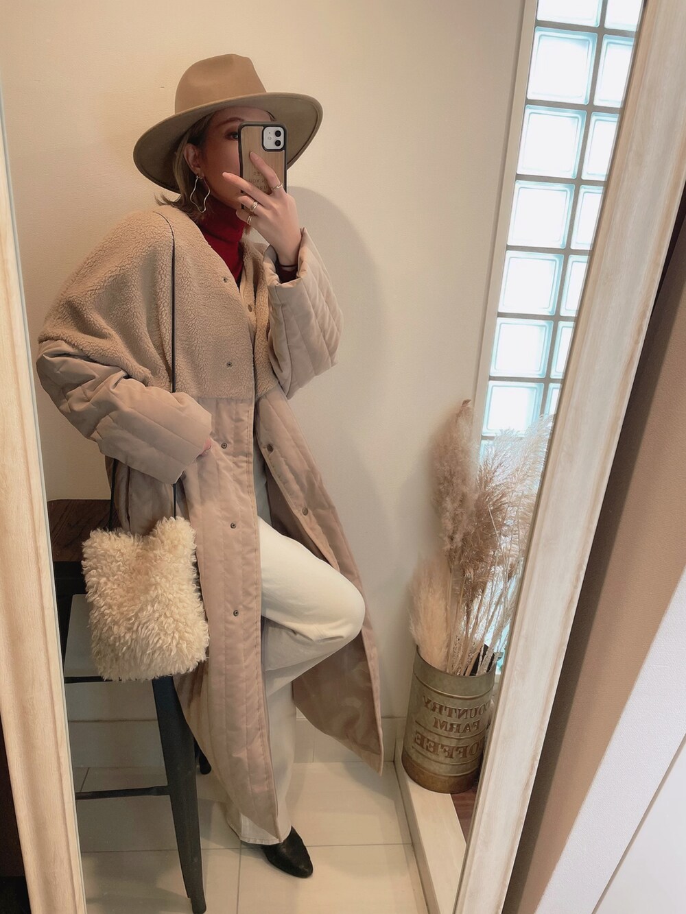 ベージュ系のノーカラーコート、ホワイト系のショルダーバッグ、ホワイト系のデニムパンツを着用したレディースの冬コーディネートの3枚目の写真