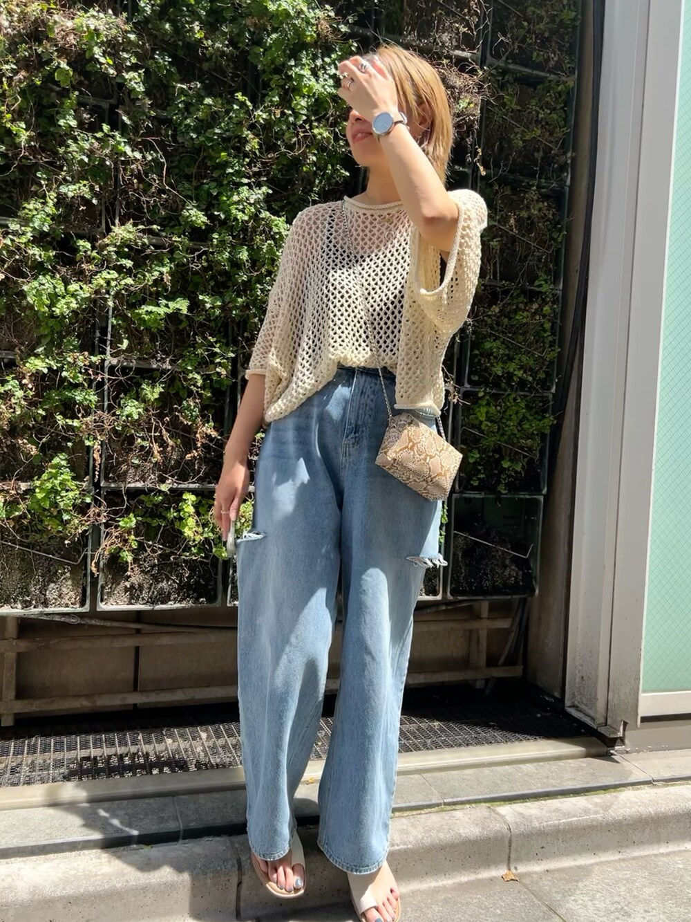 ホワイト系のニット/セーター、ブルー系のデニムパンツ、ホワイト系のサンダルを着用したレディースの春コーディネートの2枚目の写真