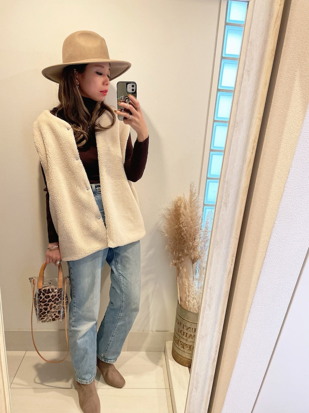 ホワイト系のベスト、ブルー系のデニムパンツ、ベージュ系のショルダーバッグを着用したレディースの秋コーディネートの3枚目の写真