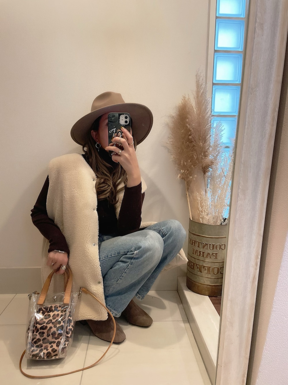 ホワイト系のベスト、ブルー系のデニムパンツ、ベージュ系のショルダーバッグを着用したレディースの秋コーディネートの2枚目の写真