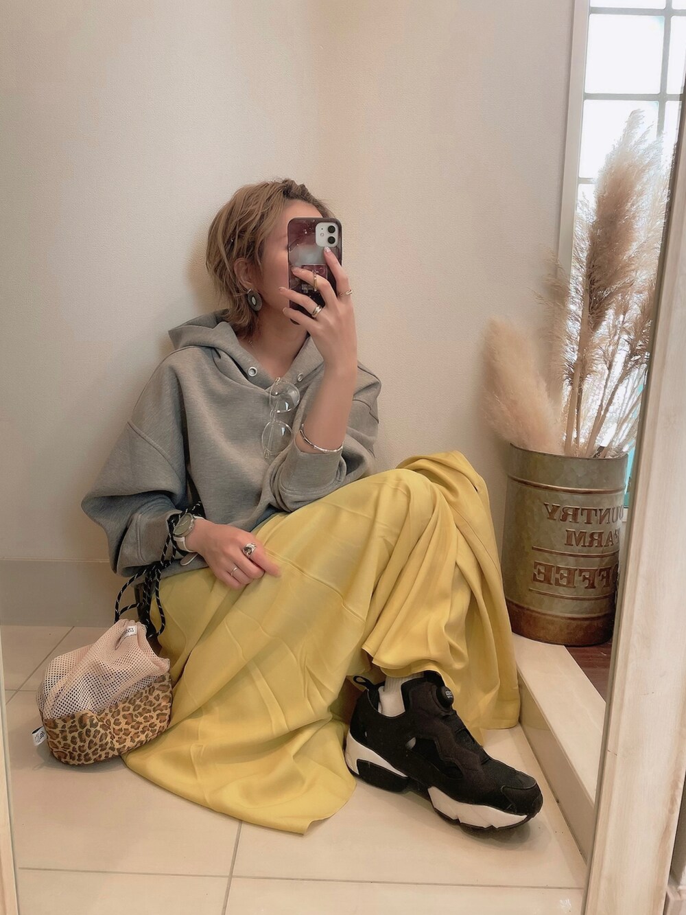 イエロー系のスカート、ブラック系のスニーカー、グレー系のパーカーを着用したレディースの春コーディネートの2枚目の写真