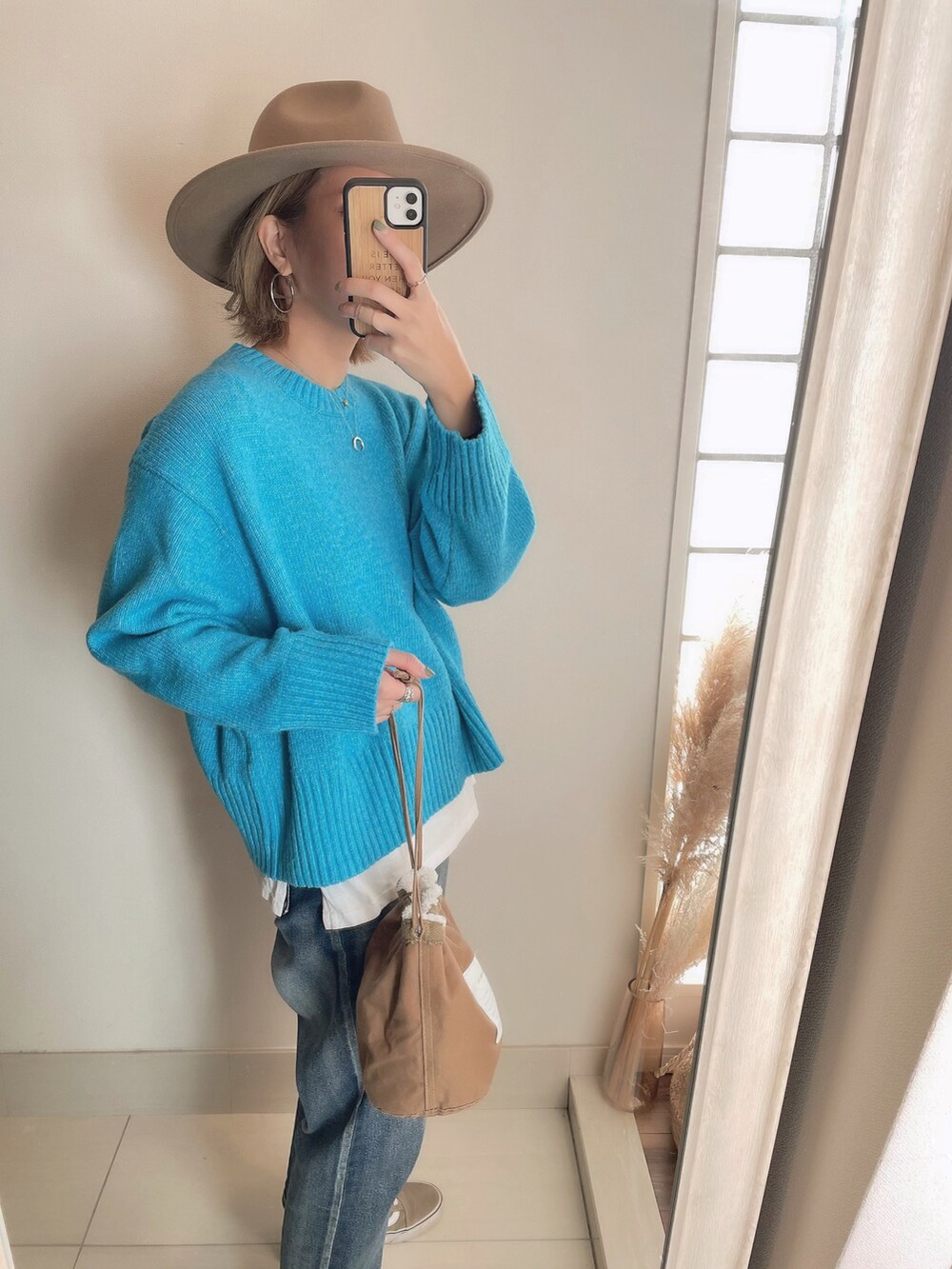 ブルー系のニット/セーター、ベージュ系のブルゾン、ブラウン系のクラッチバッグを着用したレディースの冬コーディネートの3枚目の写真