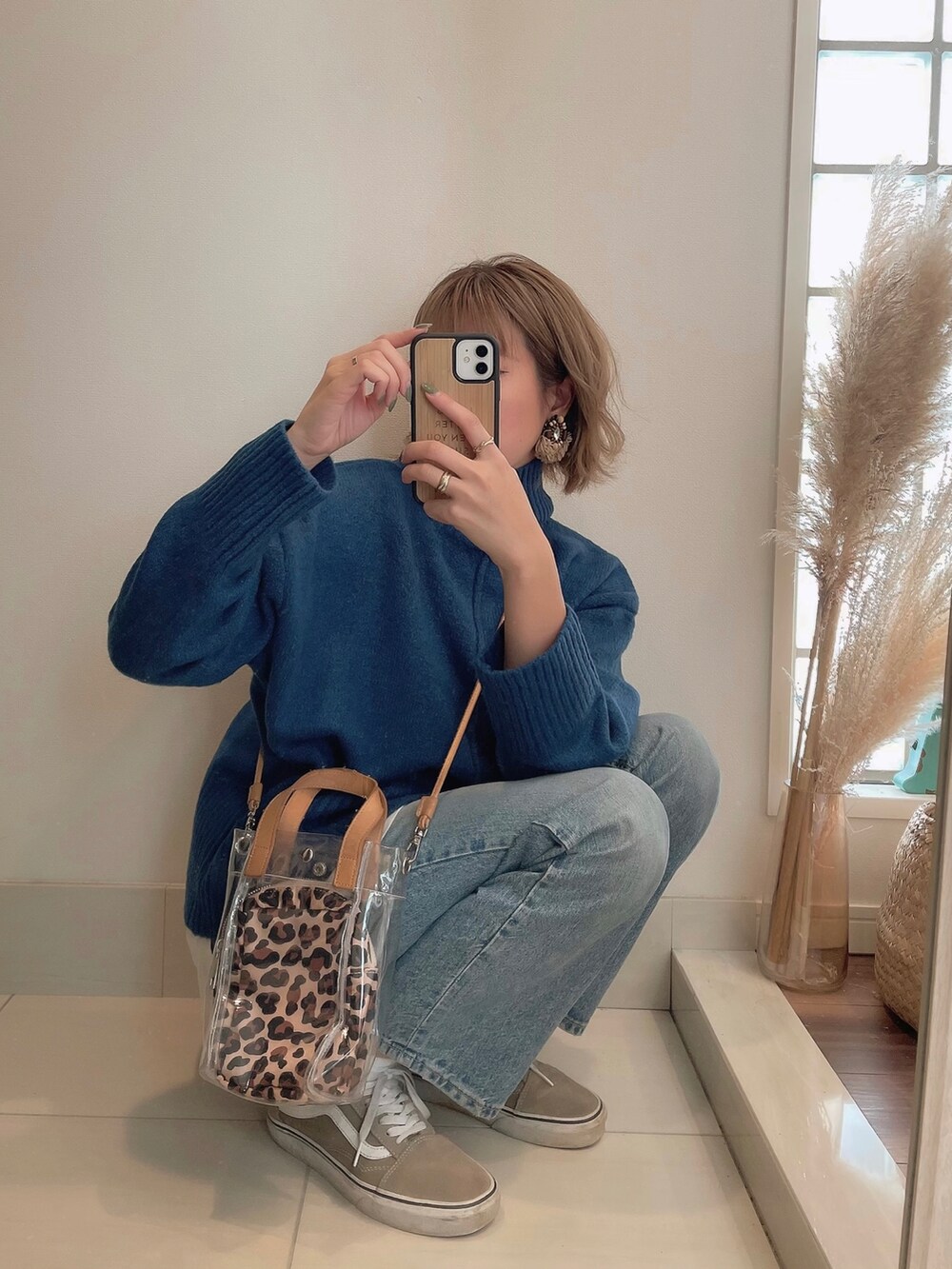ブルー系のニット/セーター、ベージュ系のショルダーバッグ、ブルー系のデニムパンツを着用したレディースの秋コーディネートの4枚目の写真