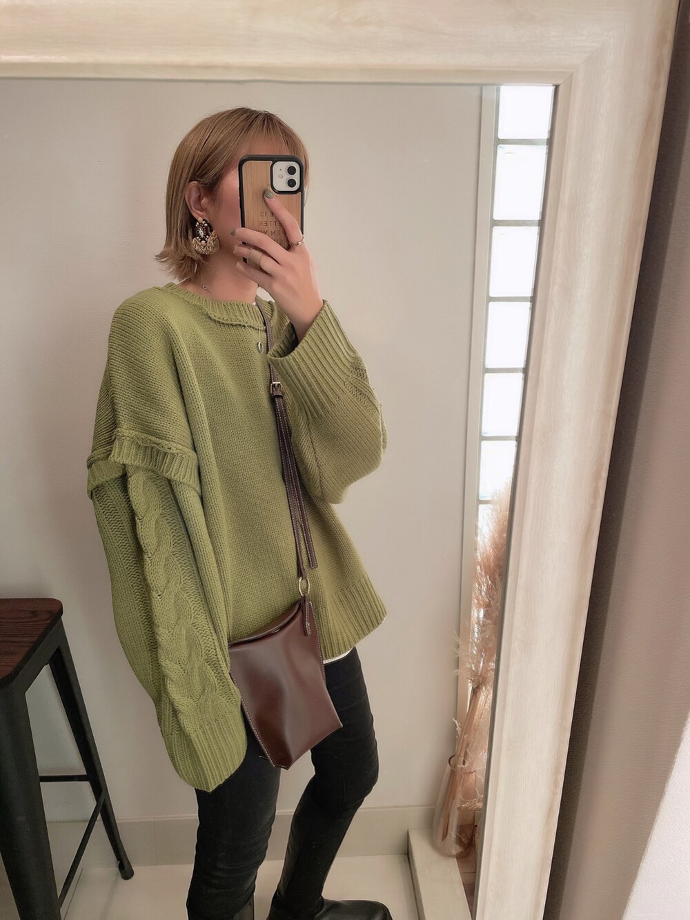 グリーン系のニット/セーター、ブラック系のブーツ、ブラック系のデニムパンツを着用したレディースの冬コーディネートの3枚目の写真