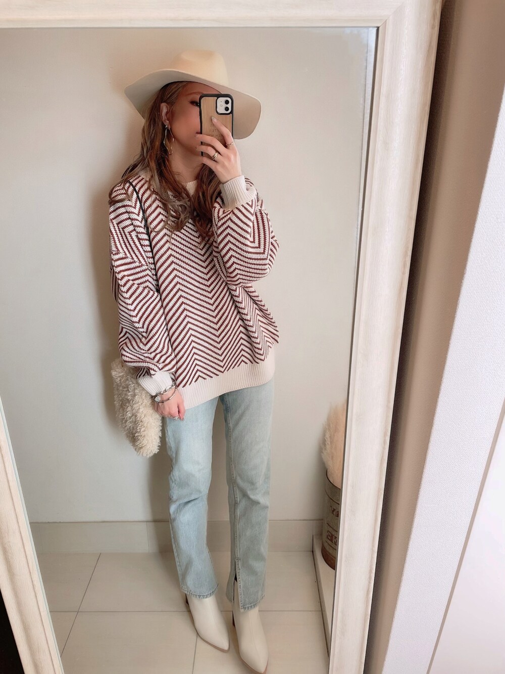 オレンジ系のニット/セーター、ホワイト系のショルダーバッグ、ホワイト系のハットを着用したレディースの冬コーディネートの3枚目の写真