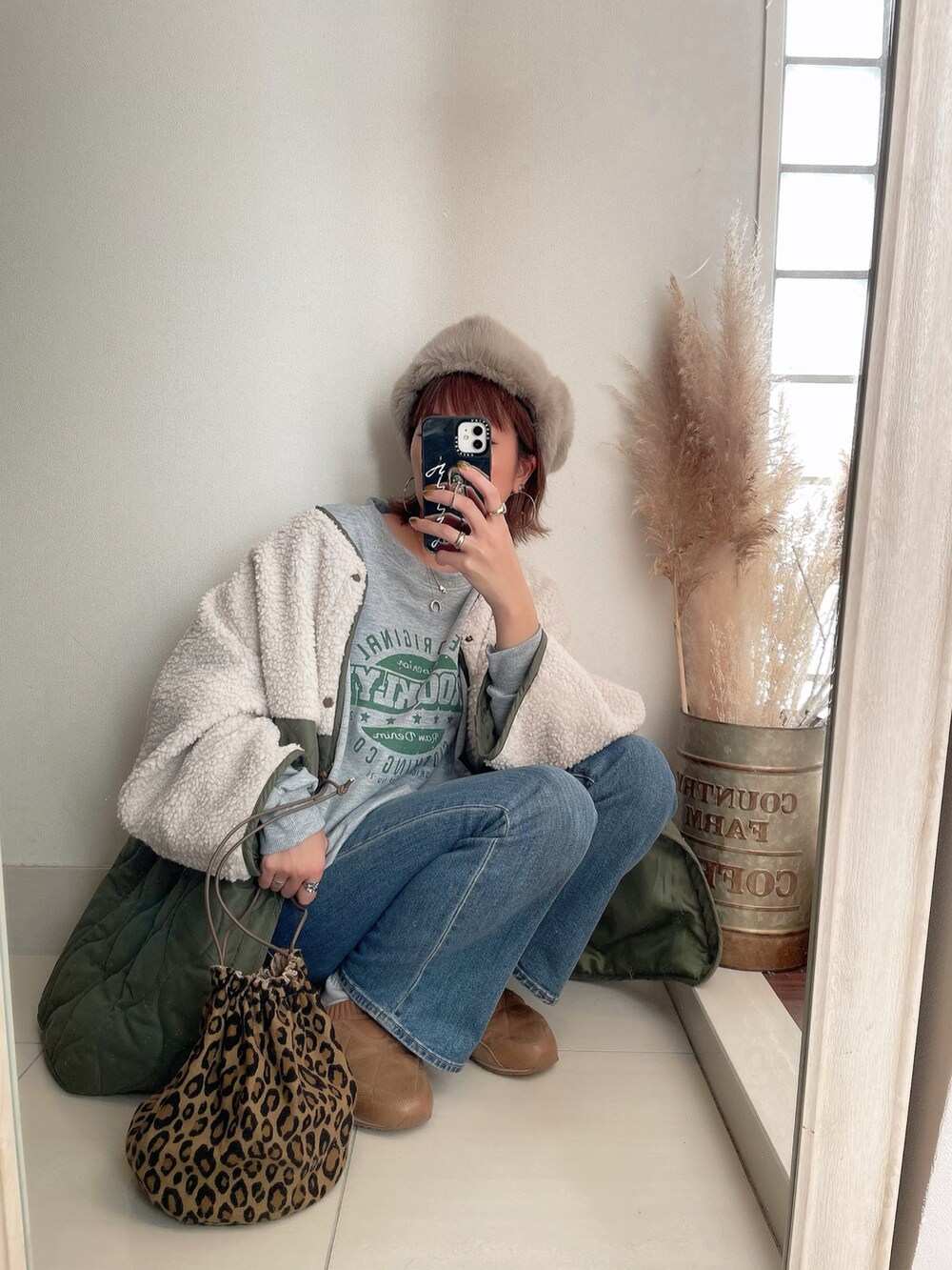 グレー系のスウェット、グリーン系のブルゾン、ブルー系のデニムパンツを着用したレディースの冬コーディネートの2枚目の写真