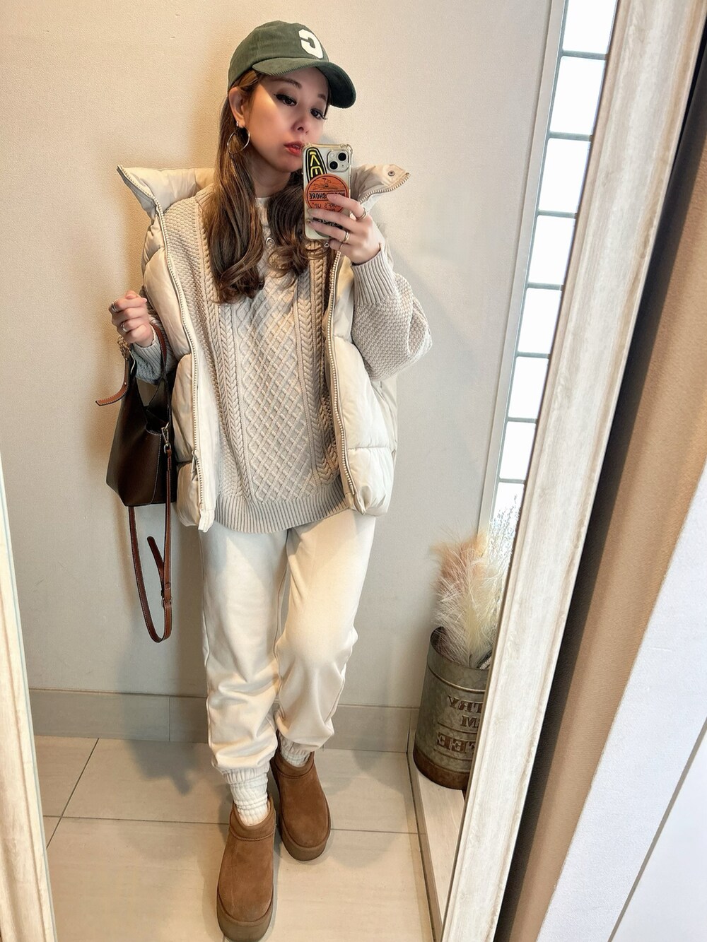 ベージュ系のニット/セーター、ベージュ系のダウンベスト、ブラウン系のブーツを着用したレディースの冬コーディネートの2枚目の写真