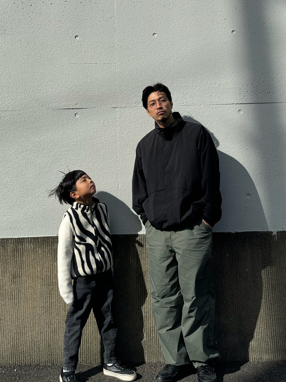 ホワイト系のベスト、ブラック系のデニムパンツ、ブラック系のスリッポンを着用したキッズの秋コーディネートの2枚目の写真