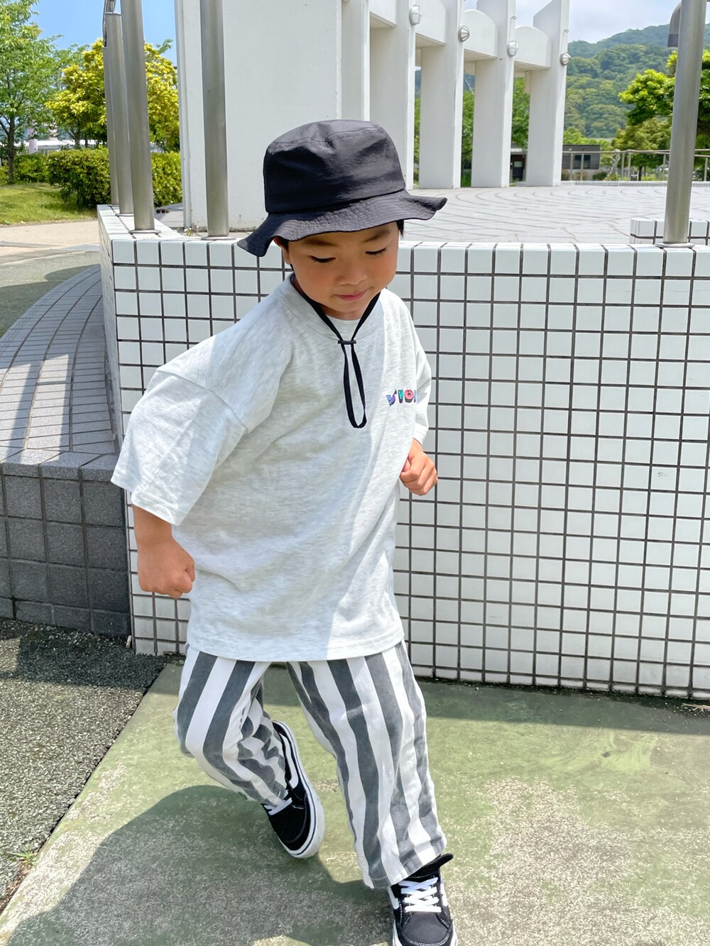 グレー系のTシャツ/カットソー、ホワイト系のパンツ、ブラック系のハットを着用したキッズの春コーディネートの3枚目の写真