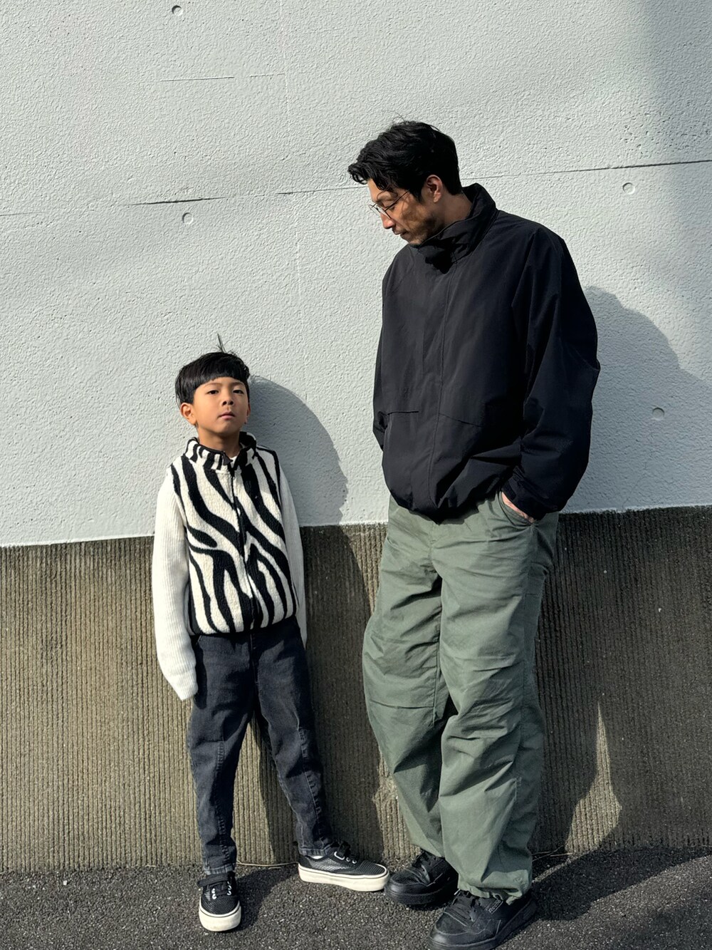 ホワイト系のベスト、ブラック系のデニムパンツ、ブラック系のスリッポンを着用したキッズの秋コーディネートの3枚目の写真