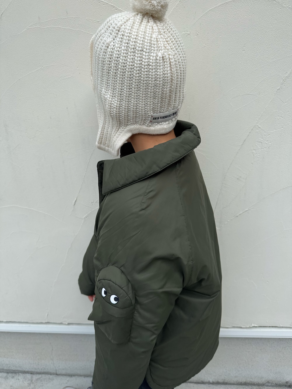 グリーン系のジャケット/アウター、ベージュ系のトップス、ブラック系のデニムパンツを着用したキッズの冬コーディネートの2枚目の写真