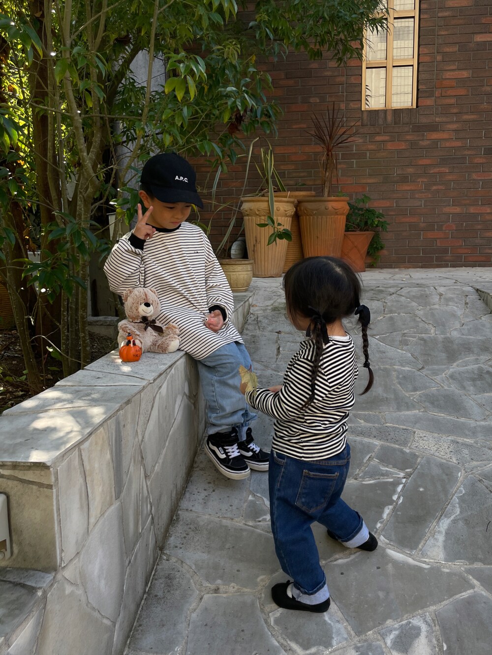 ホワイト系のトップス、ブルー系のデニムパンツ、ブラック系のスニーカーを着用したキッズの秋コーディネートの2枚目の写真