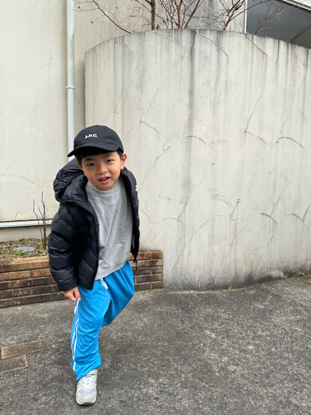 ブラック系のダウンジャケット/コート、ブルー系のその他パンツ、グレー系のスニーカーを着用したキッズの冬コーディネートの2枚目の写真