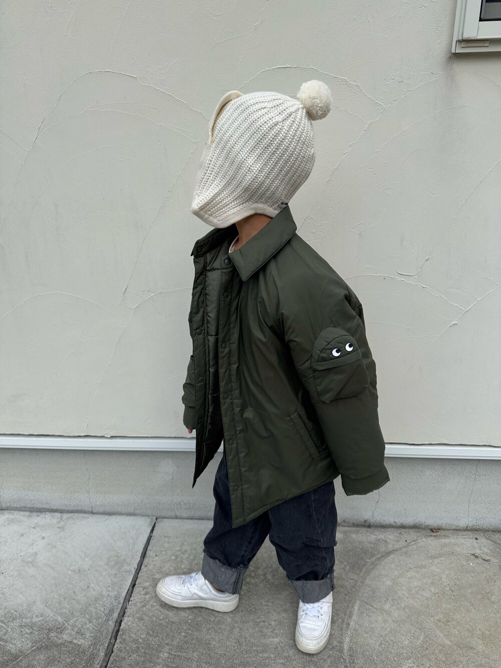 グリーン系のジャケット/アウター、ベージュ系のトップス、ブラック系のデニムパンツを着用したキッズの冬コーディネートの4枚目の写真