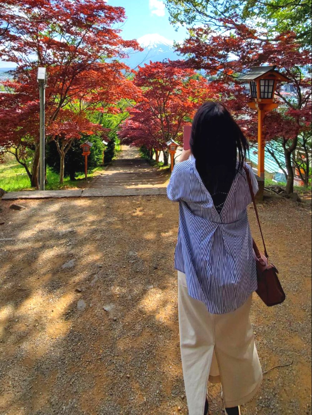 ブルー系のシャツ/ブラウス、ブラウン系のショルダーバッグ、ベージュ系のスニーカーを着用したレディースの春コーディネートの2枚目の写真