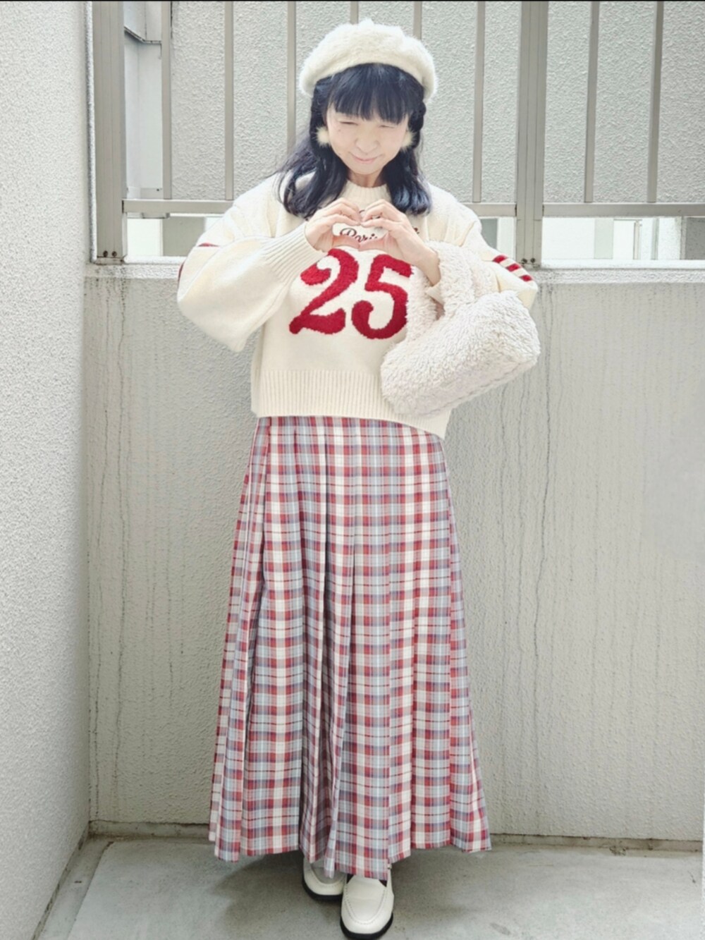 レッド系のピーコート、ホワイト系のニット/セーター、レッド系のスカートを着用したレディースの冬コーディネートの3枚目の写真