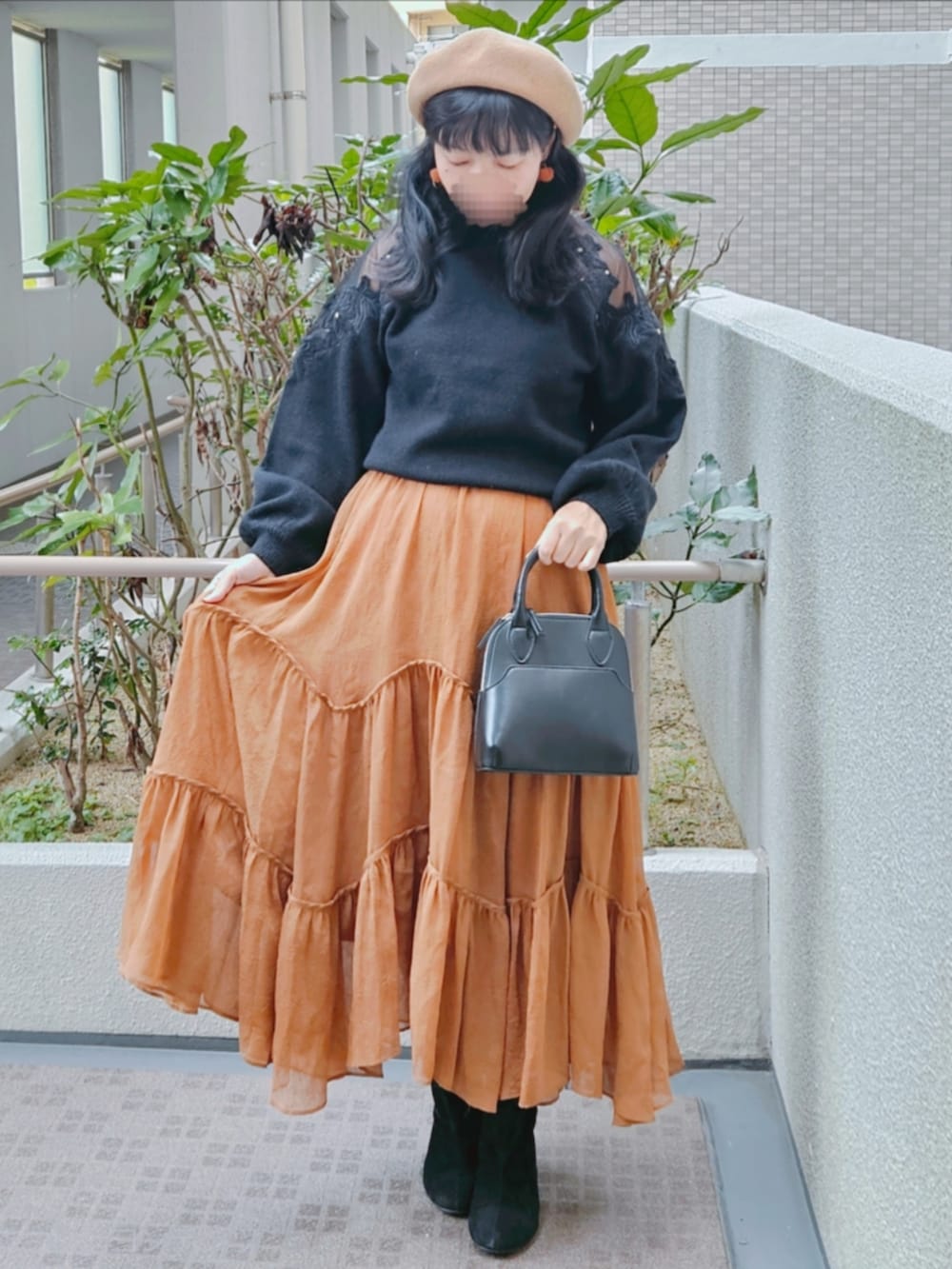 ブラック系のニット/セーター、ブラウン系のスカート、ブラック系のハンドバッグを着用したレディースの春コーディネートの2枚目の写真