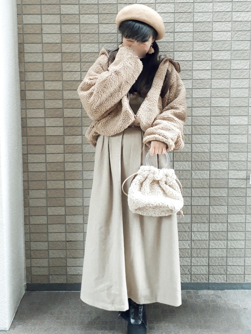 ブラウン系のブルゾン、ブラック系のニット/セーター、ベージュ系のスカートを着用したレディースの冬コーディネートの2枚目の写真