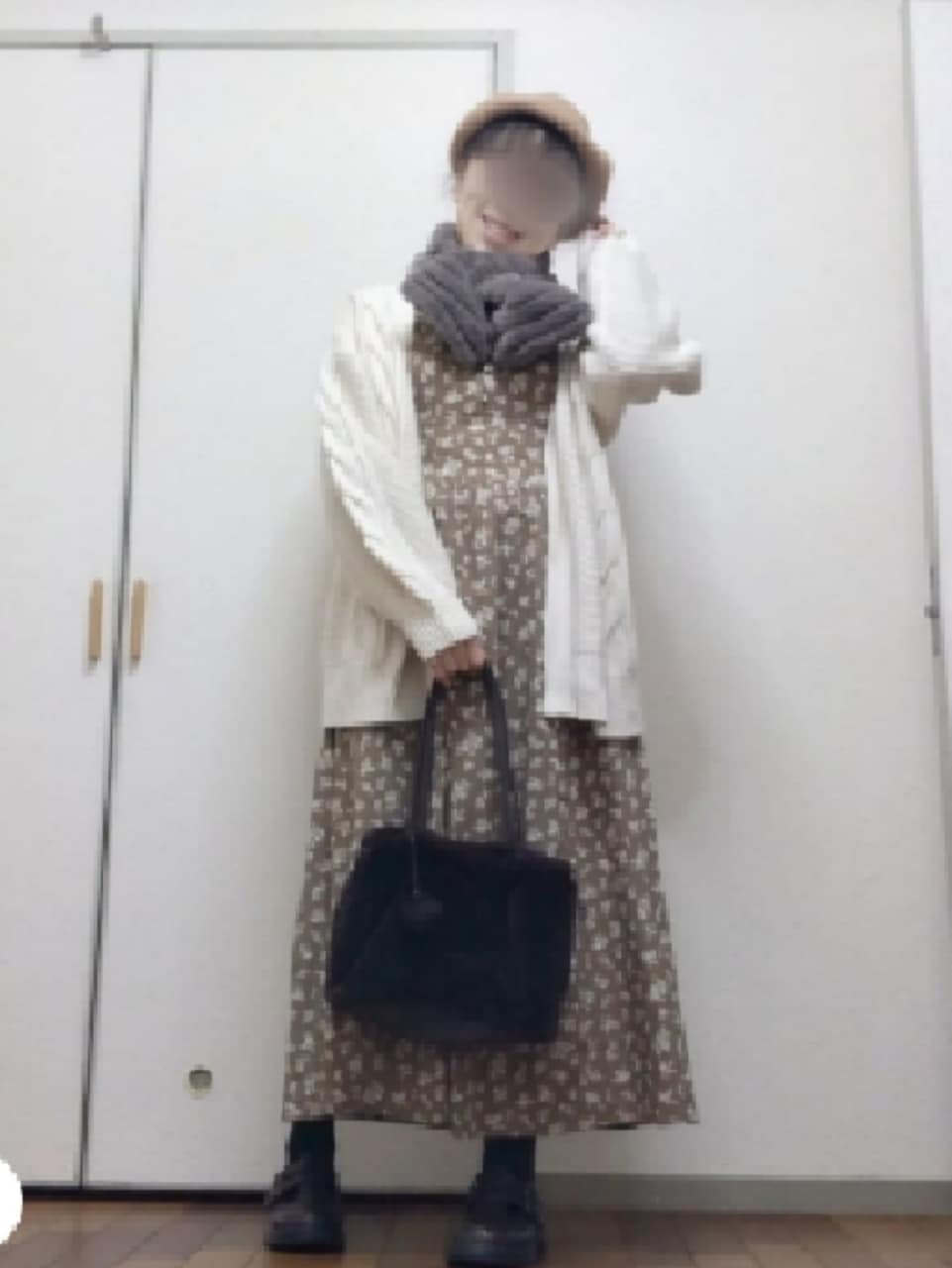 オレンジ系のワンピース、ブラウン系のイヤリング、グレー系のマフラーを着用したレディースの冬コーディネートの2枚目の写真