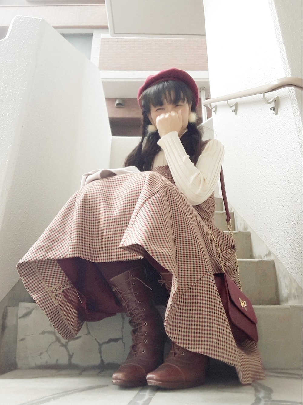 ホワイト系のトレンチコート、ブラウン系のジャンパースカート、レッド系のショルダーバッグを着用したレディースの秋コーディネートの5枚目の写真