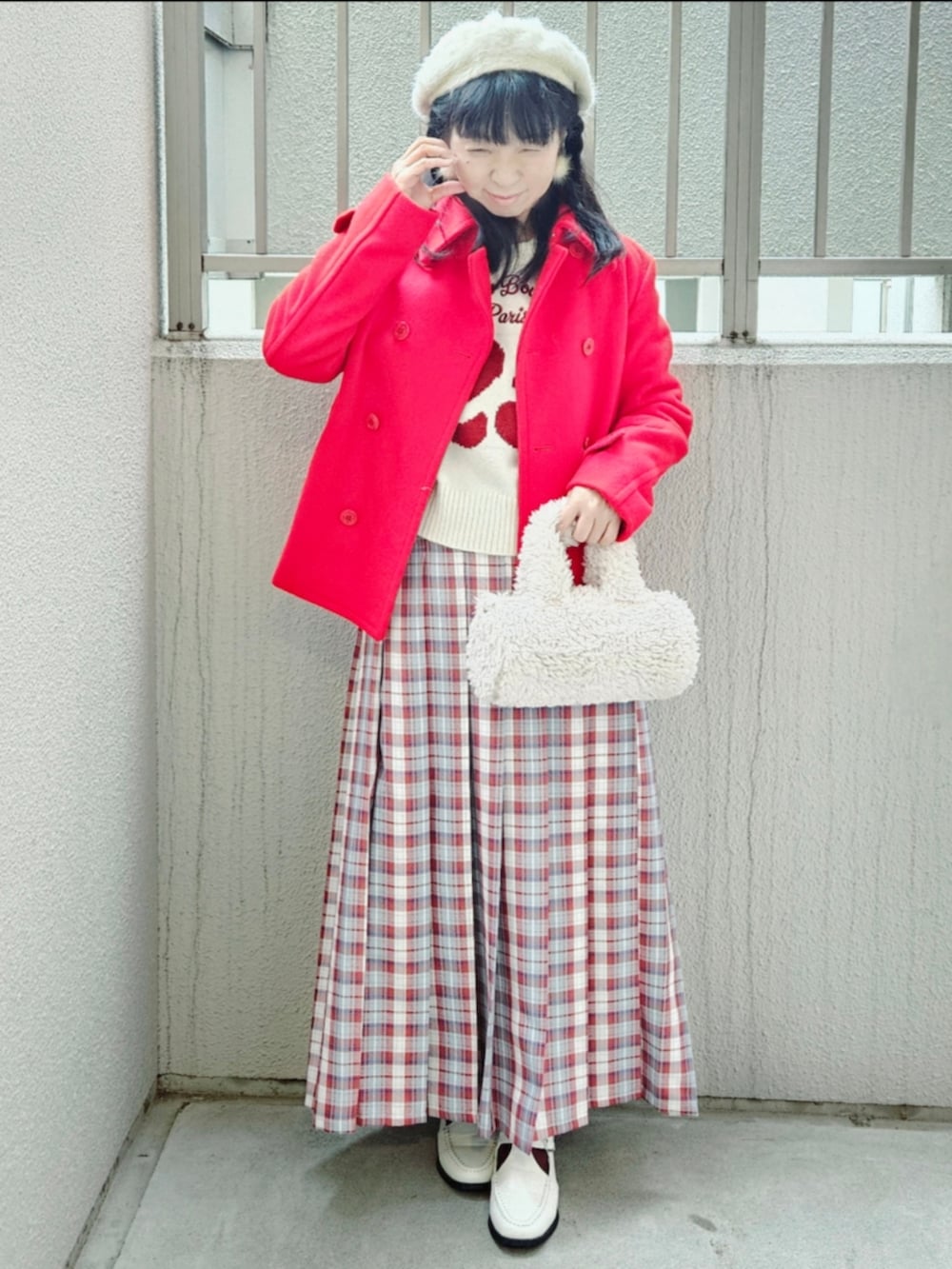 レッド系のピーコート、ホワイト系のニット/セーター、レッド系のスカートを着用したレディースの冬コーディネートの2枚目の写真