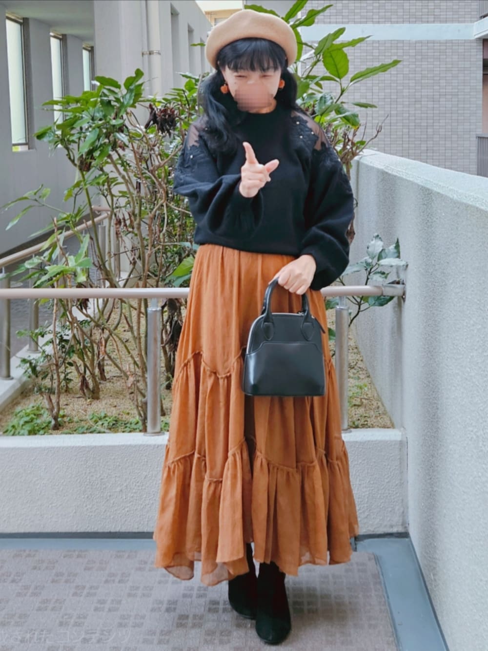 ブラック系のニット/セーター、ブラウン系のスカート、ブラック系のハンドバッグを着用したレディースの春コーディネートの3枚目の写真