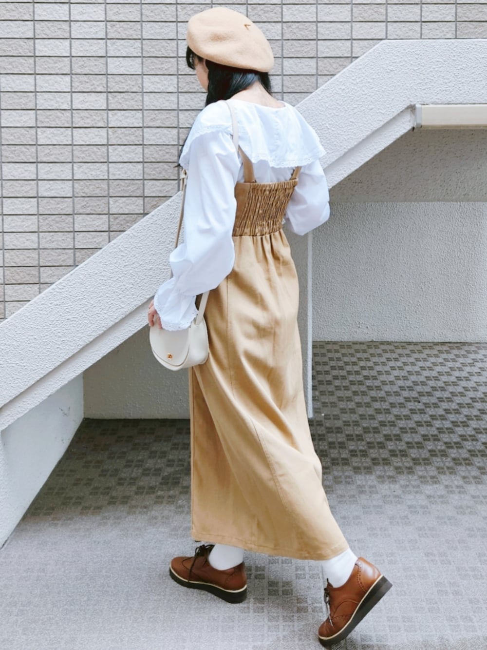 ベージュ系のジャンパースカート、ホワイト系のシャツ/ブラウス、ベージュ系のショルダーバッグを着用したレディースの秋コーディネートの5枚目の写真