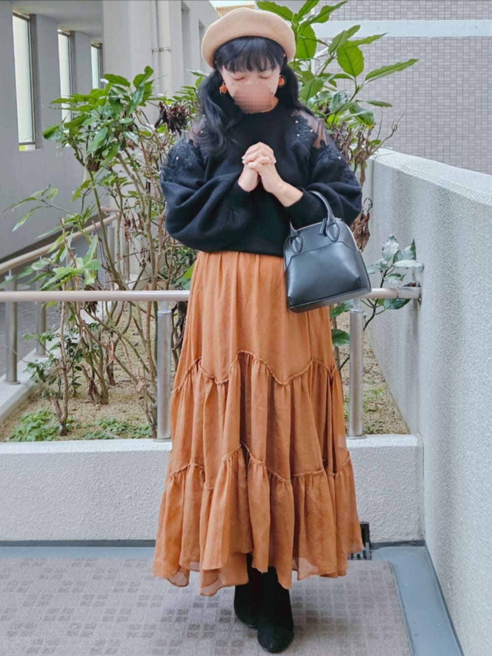 ブラック系のニット/セーター、ブラウン系のスカート、ブラック系のハンドバッグを着用したレディースの春コーディネートの4枚目の写真