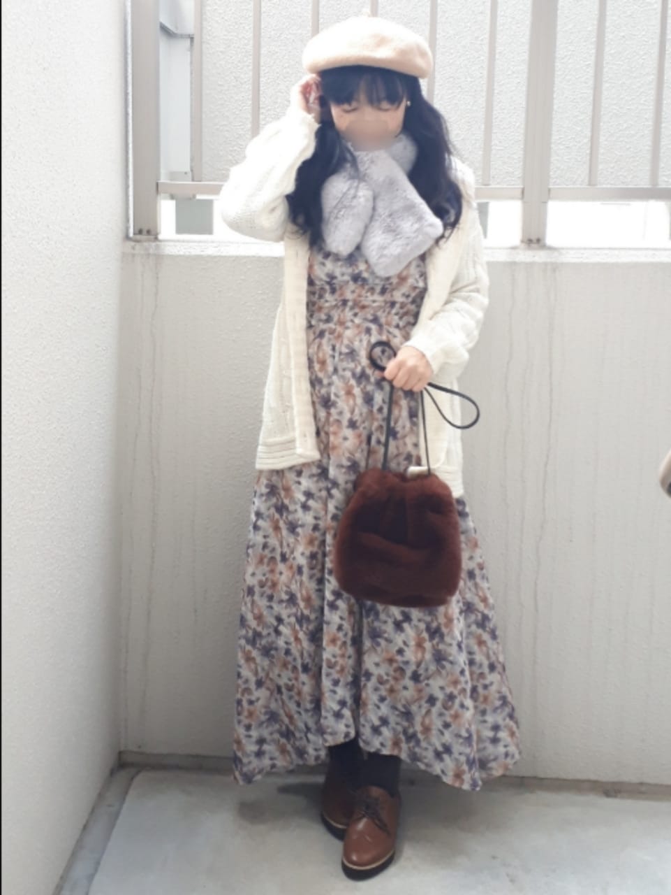 オレンジ系のワンピース、ブラウン系のイヤリング、グレー系のマフラーを着用したレディースの冬コーディネートの3枚目の写真