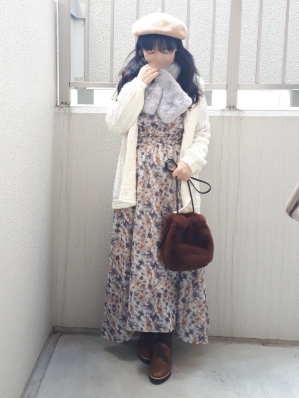 オレンジ系のワンピース、ブラウン系のイヤリング、グレー系のマフラーを着用したレディースの冬コーディネートの4枚目の写真