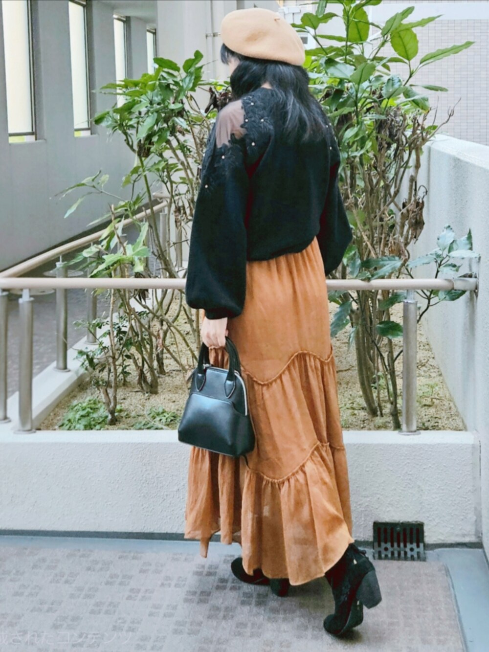 ブラック系のニット/セーター、ブラウン系のスカート、ブラック系のハンドバッグを着用したレディースの春コーディネートの5枚目の写真