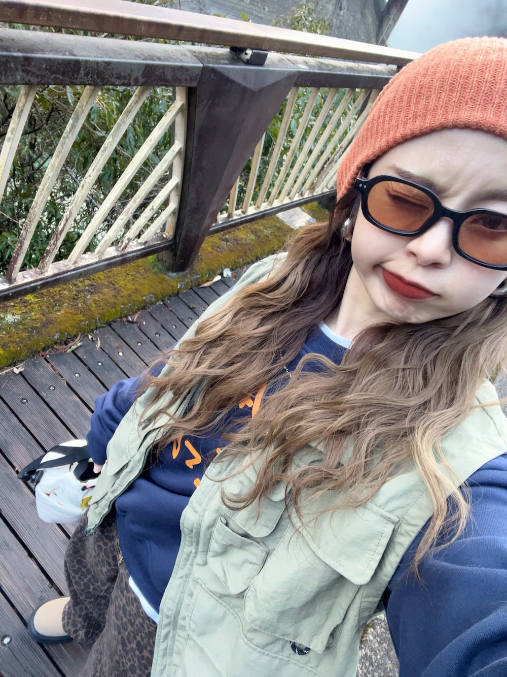 ブルー系のスウェット、グリーン系のベスト、ブラウン系のデニムパンツを着用したレディースの冬コーディネートの3枚目の写真