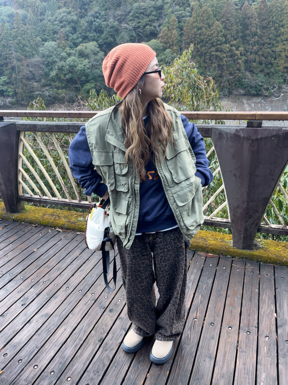 ブルー系のスウェット、グリーン系のベスト、ブラウン系のデニムパンツを着用したレディースの冬コーディネートの2枚目の写真