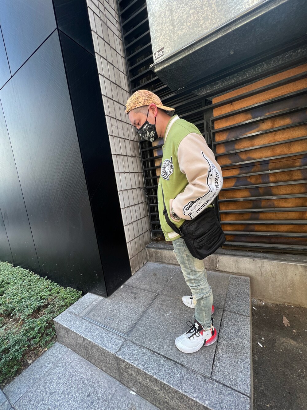 グリーン系のスタジャン、ブルー系のデニムパンツ、ホワイト系のスニーカーを着用したメンズの春コーディネートの2枚目の写真