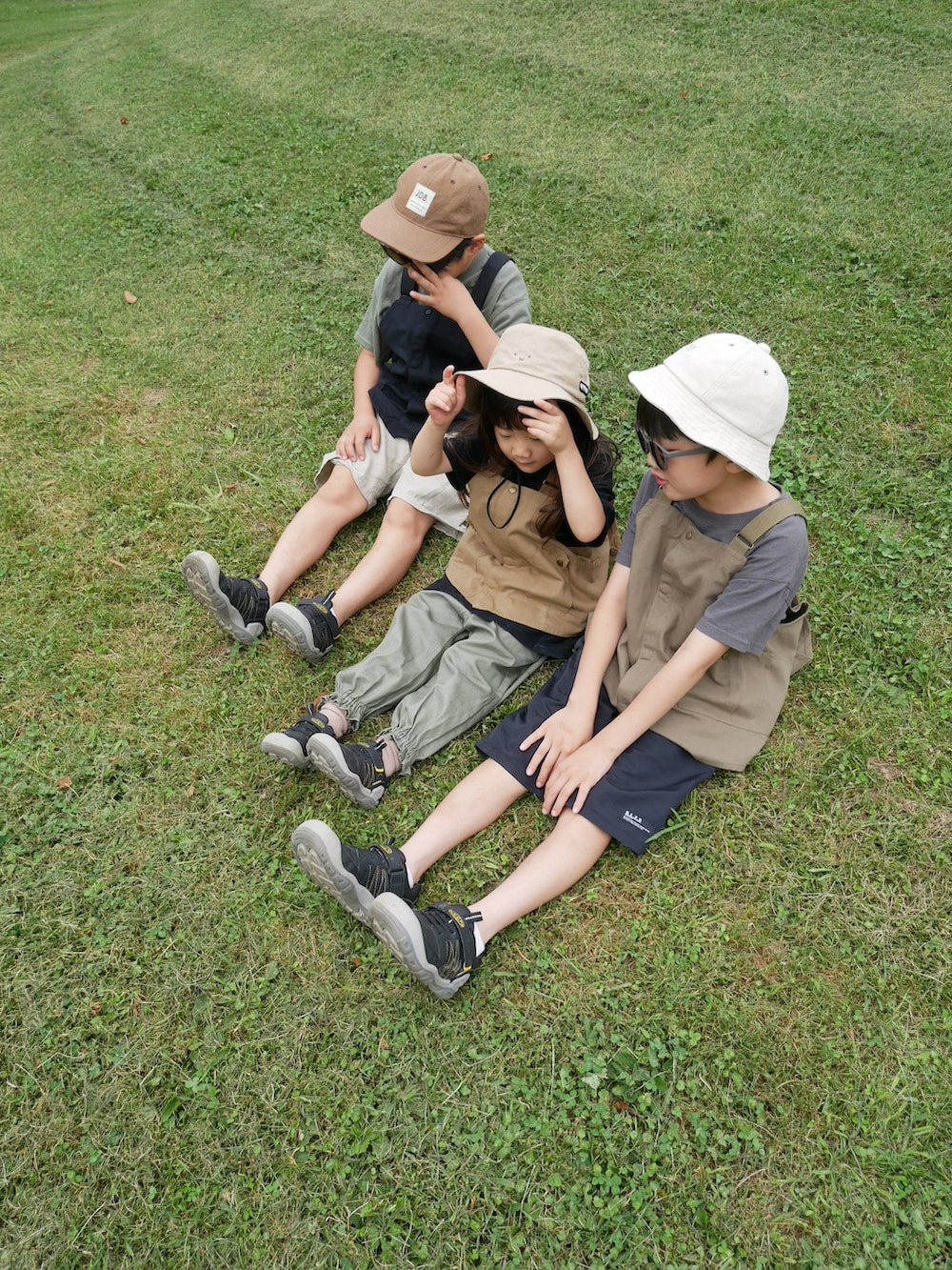 ブラック系のベスト、グリーン系のベスト、ベージュ系のベストを着用したキッズの夏コーディネートの3枚目の写真