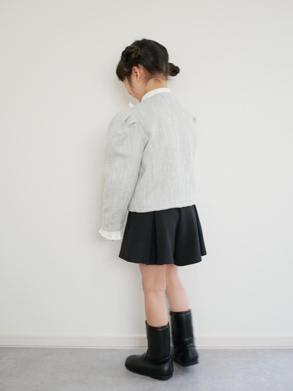 ブラック系のブーツ、ブラック系のスカート、グリーン系のノーカラーコートを着用したキッズの冬コーディネートの2枚目の写真