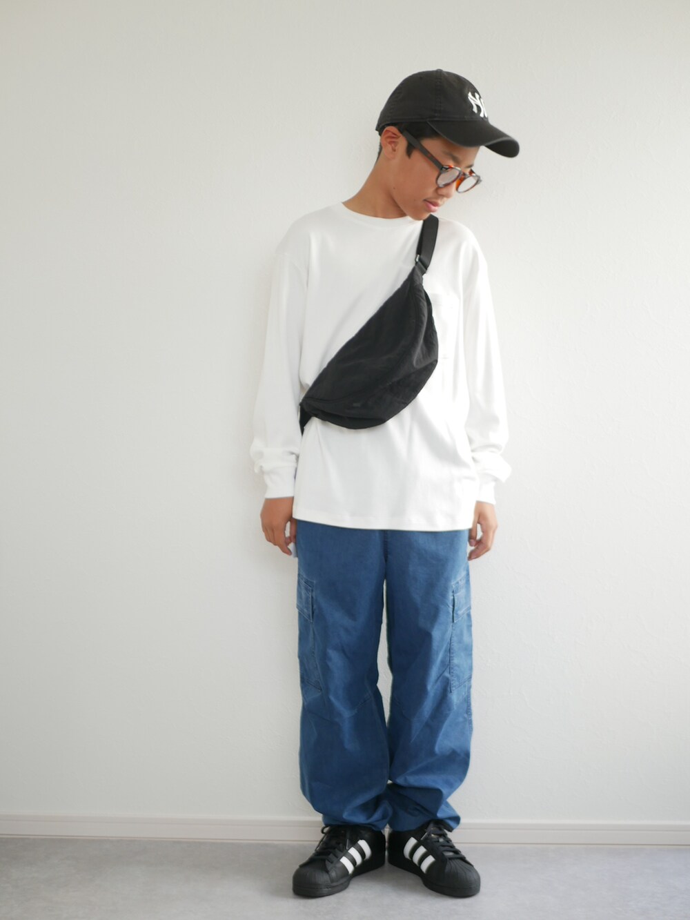 ブラック系のスニーカー、ブルー系のデニムパンツ、ブラック系のショルダーバッグを着用したキッズの秋コーディネートの2枚目の写真