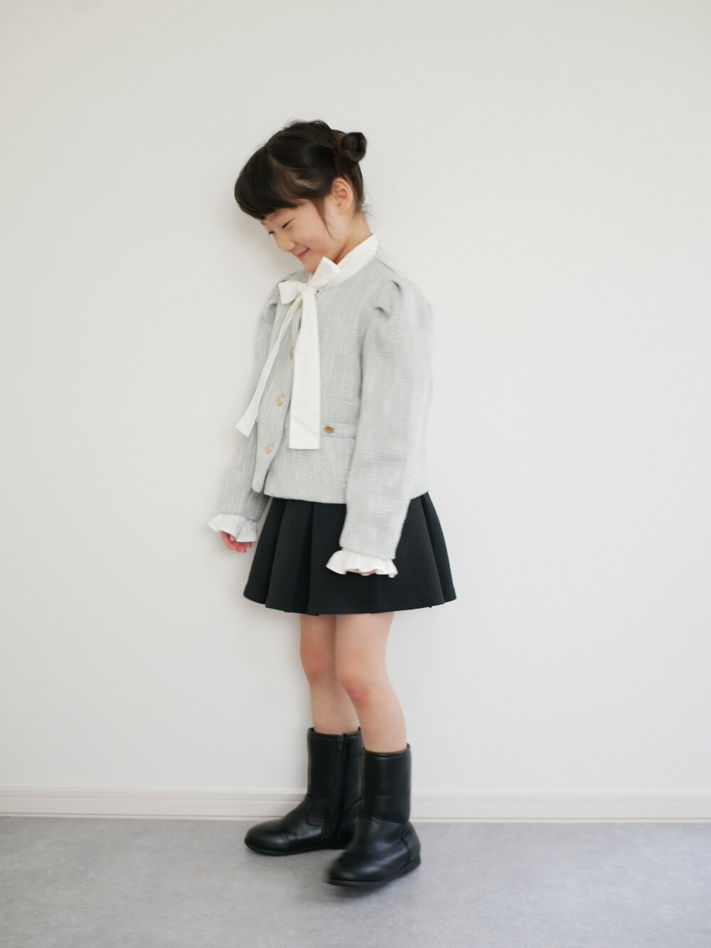 ブラック系のブーツ、ブラック系のスカート、グリーン系のノーカラーコートを着用したキッズの冬コーディネートの3枚目の写真