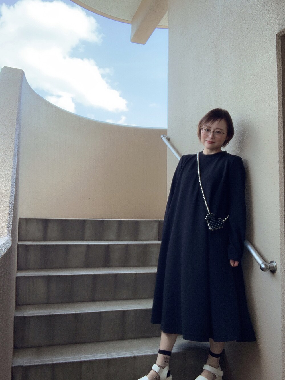 ブラック系のワンピース/ドレス、ブラック系のショルダーバッグ、ホワイト系のサンダルを着用したレディースの春コーディネートの2枚目の写真