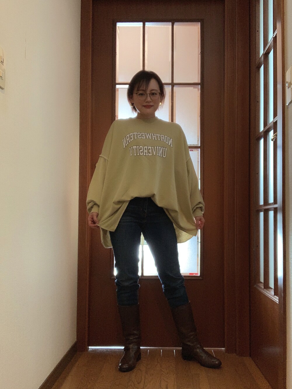 グリーン系のスウェット、ブルー系のデニムパンツ、ブラウン系のブーツを着用したレディースの春コーディネートの2枚目の写真