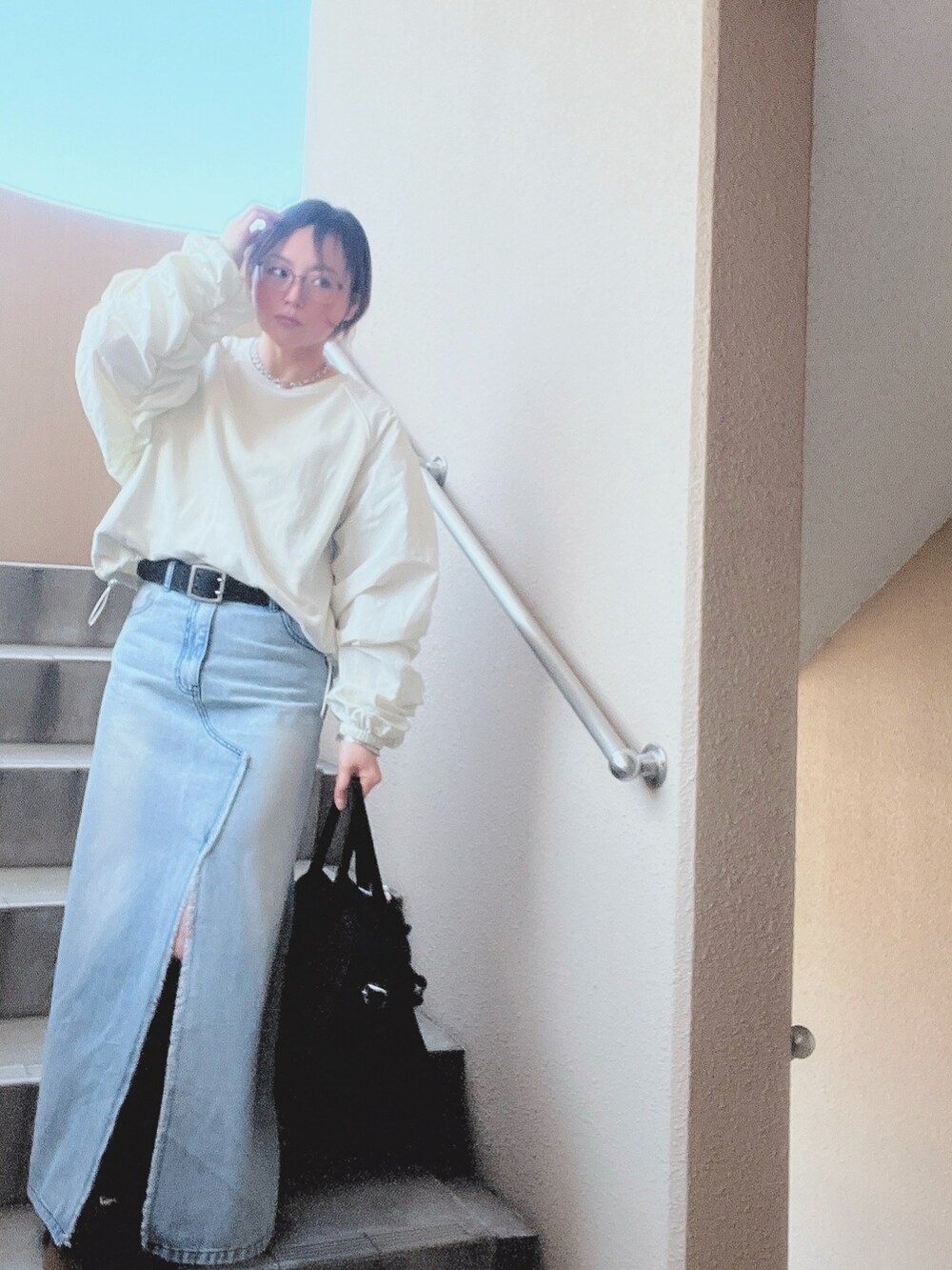 ホワイト系のスウェット、ブルー系のデニムスカート、ブラック系のスニーカーを着用したレディースの春コーディネートの3枚目の写真