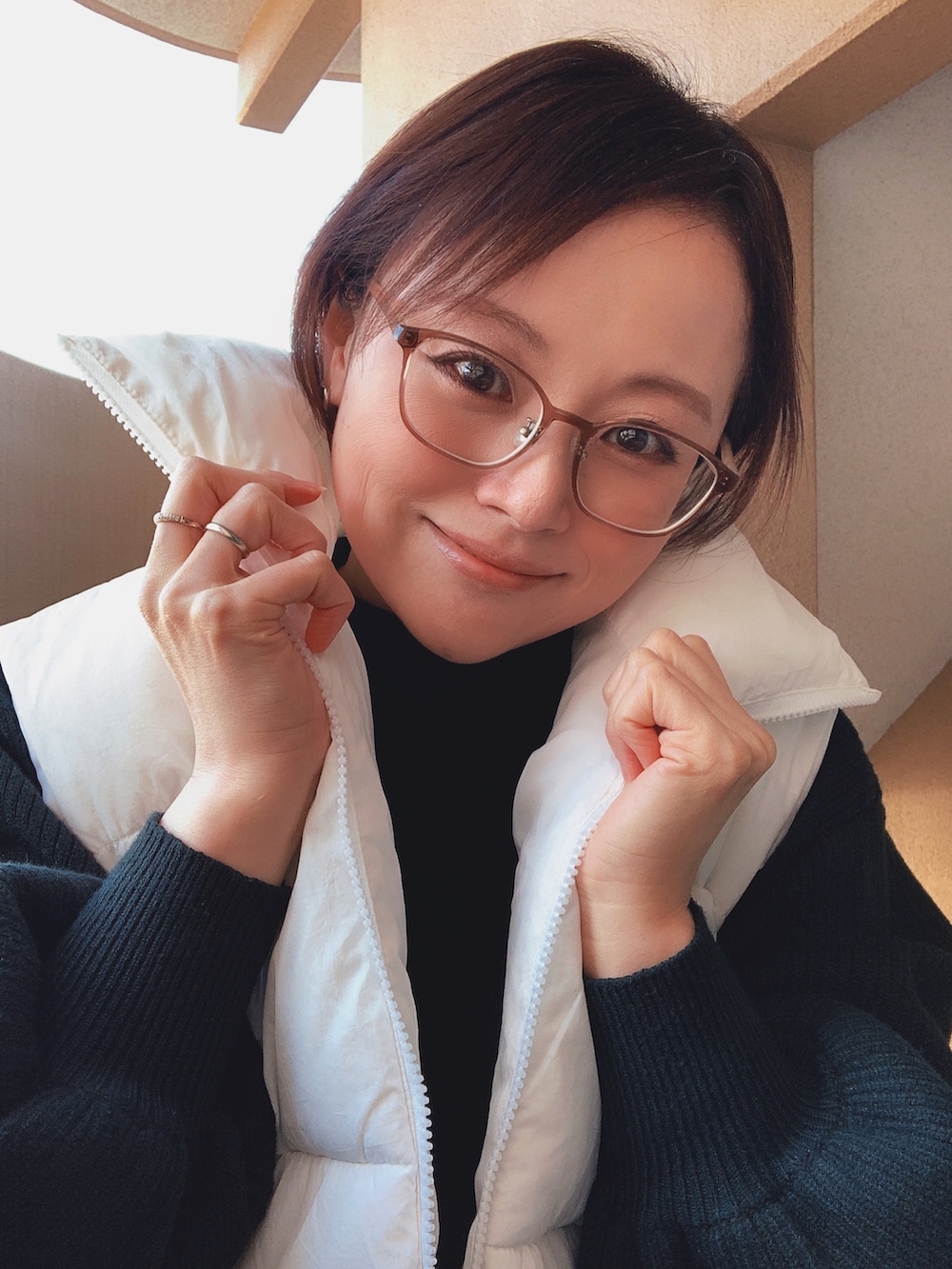 ホワイト系のダウンベスト、ブラック系のニット/セーター、ホワイト系のスカートを着用したレディースの冬コーディネートの2枚目の写真