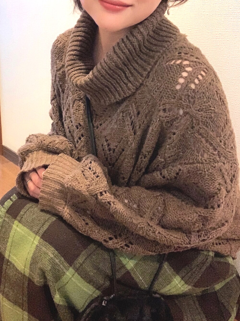 ブラウン系のニット/セーター、ブラック系のショルダーバッグ、グリーン系のスカートを着用したレディースの冬コーディネートの2枚目の写真